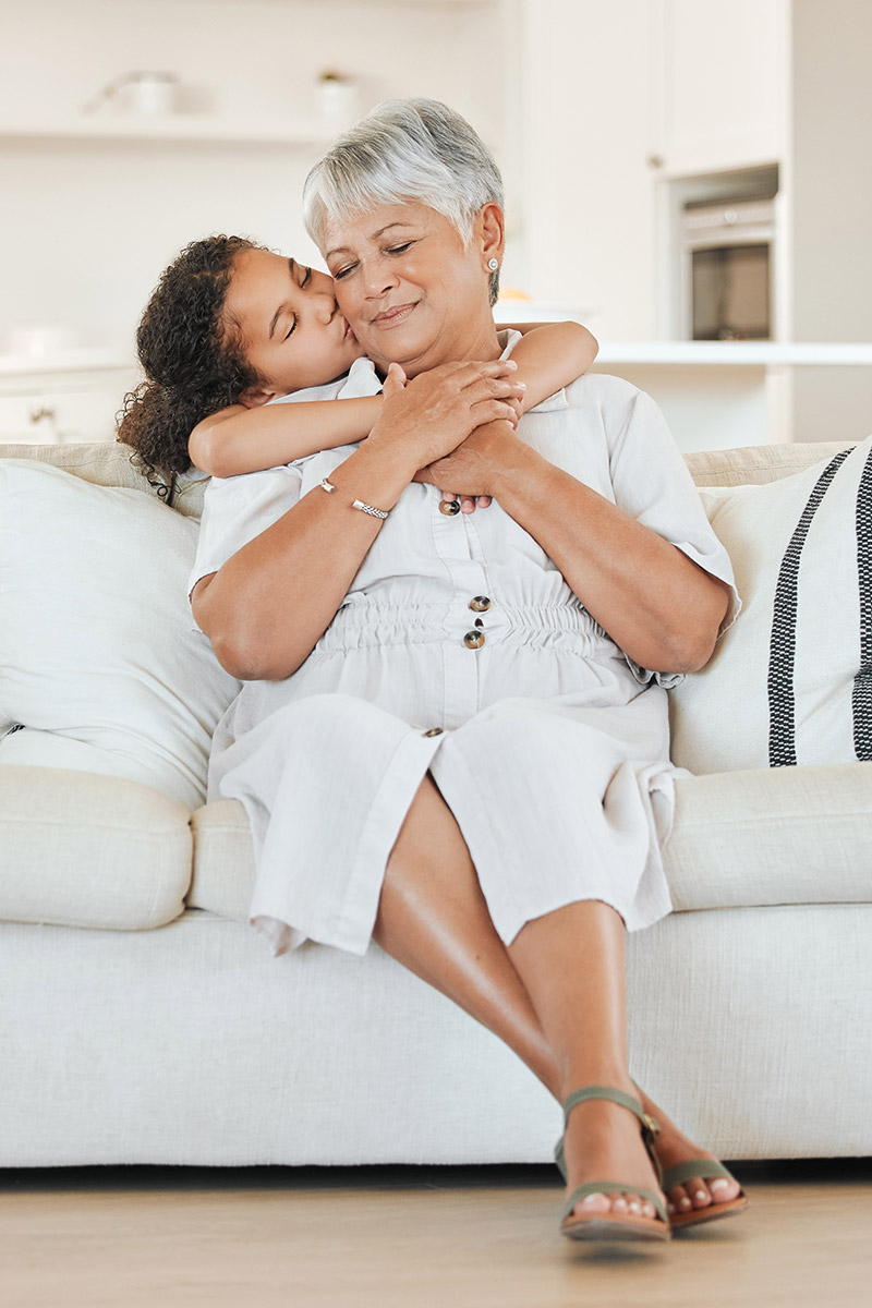 Granddaughter lovingly hugs grandma in a bright living room symbolizing the flexibility and confidence gained when working with HomeBridge Living
